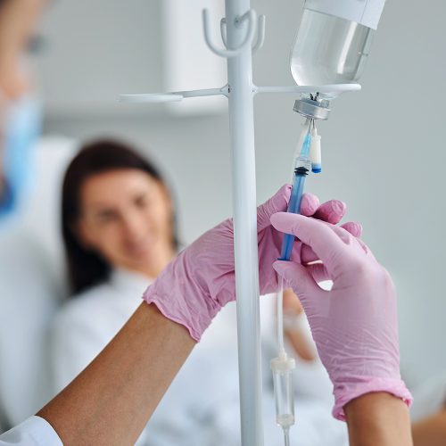 experienced-caucasian-heath-care-worker-preparing-dark-haired-female-patient-intravenous-vitamin-therapy
